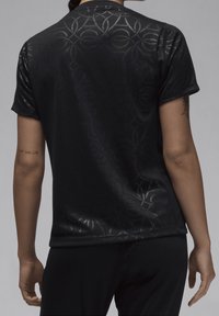 Camisa negra de manga corta con un sutil patrón circular, hecha de un material suave y ligero. Cuello redondo y ajuste relajado.