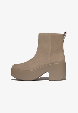 Bottes cheville en daim beige avec une semelle plateforme épaisse et un talon bloc. Dotées d'une languette à l'arrière pour un enfilage facile.