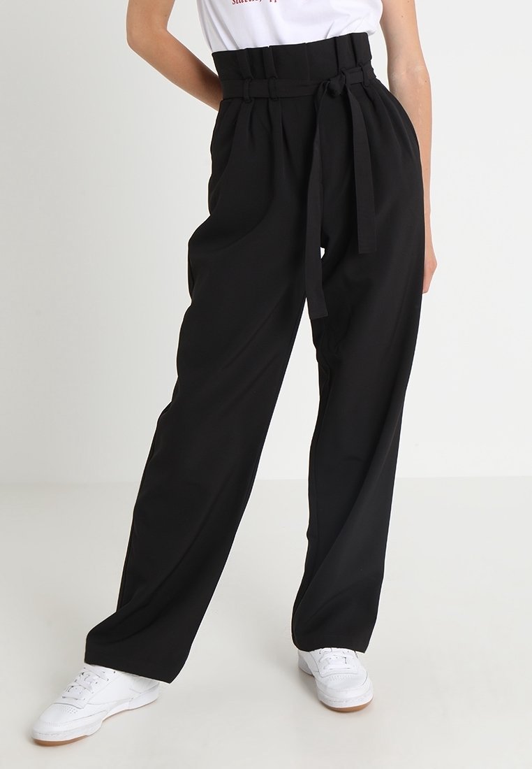 Pantalons noirs taille haute avec une jambe large, dotés d'une ceinture nouée à la taille. Le tissu semble lisse avec une coupe structurée.