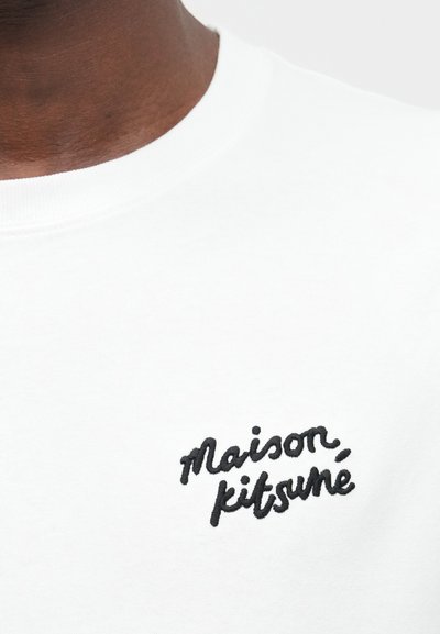 Bijela dukserica s crnim vezom "maison, kitsuné" na lijevoj strani grudnog koša. Glatka pamučna tkanina s dizajnom okruglog izreza.