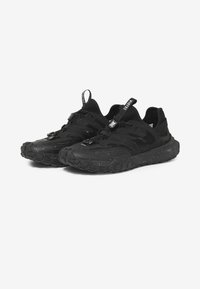 Schwarze Sportschuhe mit einem strukturierten Design, Netzpaneelen, einer gesprenkelten Sohle und einem Zugschirmsystem, ausgestattet mit Zuglaschen für ein einfaches An- und Ausziehen.