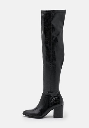 Black knee-high boots made of shiny faux crocodile skin, featuring a pointed toe and a chunky, square heel. Smooth texture throughout.