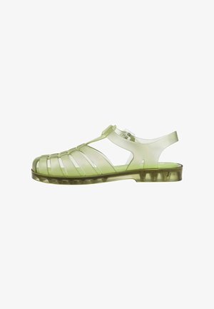 Transparante groene sandalen met een riempjesontwerp, een platte zool en een hielband aan de achterkant. Gemaakt van flexibel en duurzaam kunststof.