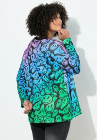 Camicia oversize colorata con un motivo ripetuto di facce sorridenti in verde, blu e viola su uno sfondo nero. Maniche lunghe, texture liscia.