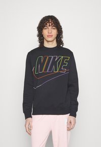 Juodas megztinis su ryškiu daugiaspalviu "NIKE" logotipu centre, pagamintas iš minkštos medžiagos su apvaliame kakle ir tiesiais manžetais.