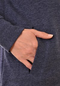 Sweatshirt bleu marine avec une finition douce et texturée ; présente une main reposant dans une poche latérale, mettant en valeur le design sans couture de la poche.
