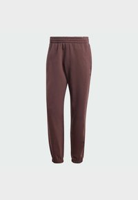 Pantaloni della tuta bordeaux con vita elasticizzata, gambe affusolate e polsini elastici alle caviglie. Presentano tasche laterali e un dettaglio del logo minimale.