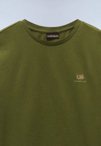 Olivgrünes T-Shirt mit kurzen Ärmeln und Rundhalsausschnitt, mit einem kleinen, in Beige gestickten Logo auf der Brust. Aus weichem Baumwollmaterial.
