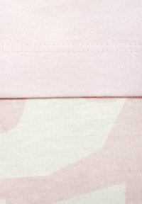 Pink cotton fabric with ribbed texture at the top, layered over patterned off-white fabric featuring light pink abstract shapes.