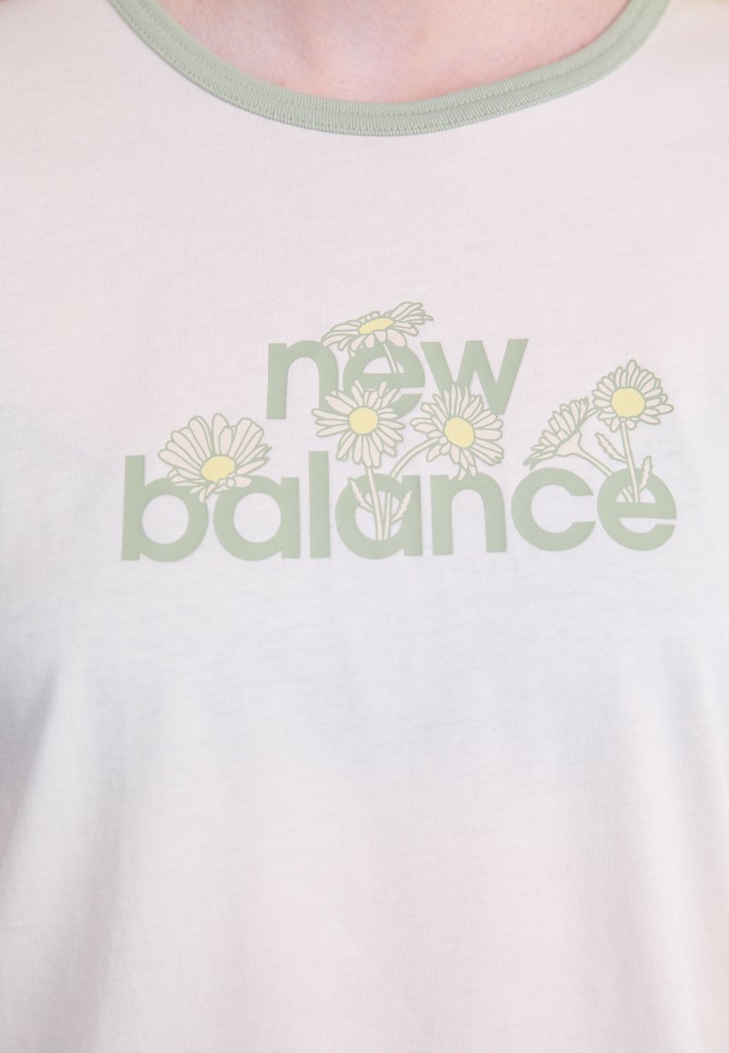 T-shirt in cotone chiaro con colletto verde a rotondo, con stampa del testo "new balance" e grafiche di fiori gialli.