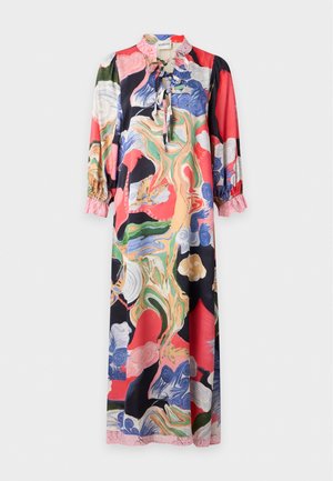 Femme portant une longue robe colorée à imprimé abstrait avec un bord en dentelle rose, tenant un sac à main beige et portant des ballerines beiges.