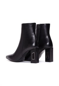 Czarne skórzane botki za kostkę z przeszywanym czubkiem oraz masywnymi blokowymi obcasami z prostokątnymi wycięciami. Zapięcie na zamek z tyłu.