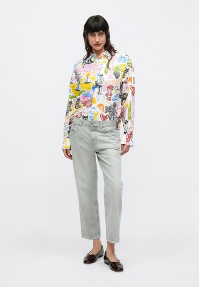 Chemise colorée à manches longues avec divers graphismes, associée à un jean gris clair à jambes droites et des chaussures sombres et élégantes. Éléments de design simples.