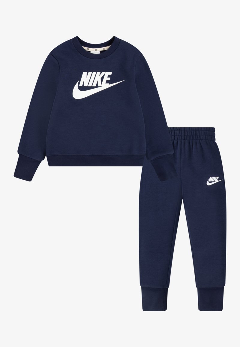 Sweatshirt bleu marine avec logo Nike blanc, col ras du cou et poignets côtelés, associé à un jogging élastique assorti avec des accents de logo.