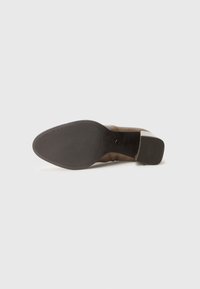 Suede brown ankle boot with a textured outsole, a rounded toe, and a low block heel, featuring branding on the sole.