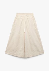 Bredde ben cremede bukser med elastisk talje og to baglommer, vist fladt mod en hvid baggrund.