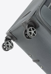 Valigia grigia con tessuto texture, manico retraibile e ruote girevoli duali. Presenta dettagli in plastica e un compartimento con zip.