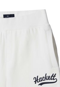 Pantalones deportivos blancos con una cinturilla acanalada, bolsillos laterales y un logo azul marino "Hackett" bordado en el muslo izquierdo. Material suave de algodón.