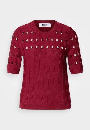 Rdeča pletena jopica s kratkimi rokavi, ki ima rebrasto teksturo in odprte luknje v vzorcu po prsih in rokavih.