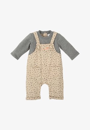 Salopette beige avec des manches longues grises, présentant un motif à carreaux répétitif, deux poches avant et un graphique de renard sur la bavette.