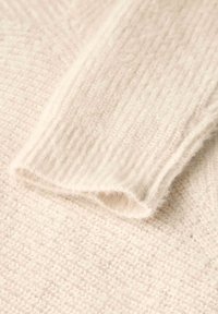 Strickpullover im Cremefarbton mit einem weichen, strukturierten Stoff, sichtbarem Rippenmuster an den Bündchen und einer lockeren Webart.