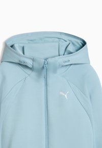 Sweat à capuche zippé bleu clair avec capuche, panneaux latéraux en maille et logo Puma blanc sur le côté gauche de la poitrine.