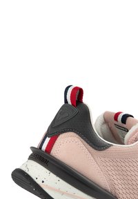 Sneaker rosa con un upper in mesh texturizzato, accentuato da un tallone in pelle nera e un tassello di trazione rosso, bianco e navy sul retro.