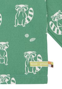 Tessuto verde con un motivo di procioni in bianco. Include un'etichetta "loud + proud" con un ACCENTO multicolore.