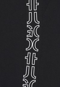 Zwarte stof met een verticale witte grafische patroon met gestileerde letters en symbolen langs de zijkant. Zachte textuur. Ontworpen voor casual kleding.