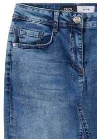 Jean en denim bleu avec poche avant, petite poche à pièces, passants de ceinture, bouton métallique et étiquette "Cecil Denim" visible à l'intérieur de la ceinture.