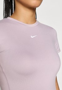 Αθλητική κοντομάνικη μπλούζα σε ανοιχτό μωβ χρώμα, με στρογγυλή λαιμόκοψη και μικρό  λογότυπο Nike σε λευκό χρώμα στο στήθος. Λείο υφασμά.