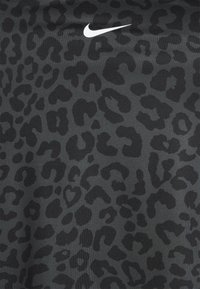 Tecido atlético preto com uma impressão de leopardo subtil em várias tonalidades de preto. Apresenta um logótipo branco da Nike no canto superior esquerdo.
