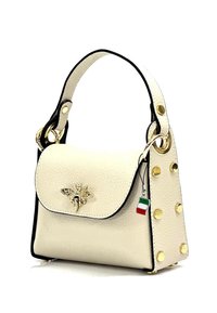 Crème leren handtas met een gestructureerd oppervlak, zwarte accenten, gouden hardware en een bij-embleem; beschikt over decoratieve gouden studs aan de zijkant.
