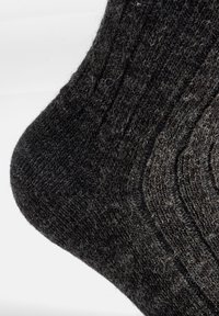 Calcetín negro de punto con un patrón texturizado y un acabado suave y difuso, con detalles acanalados en la superficie.