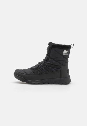 Zwarte geïsoleerde winterlaarzen met een bovenwerk van gequilt nylon, een kraag van fauxbont en een rubberen buitenzool voor grip. Met Sorel-logo op de zijkant.