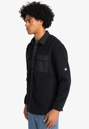 Schwarze Fleecejacke mit Knopfleiste, zwei Brusttaschen und strukturiertem Finish. Enthält ein Markenlogo am Ärmel.
