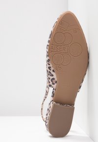 Chaussure pour femme à bride arrière avec imprimé léopard montrant la semelle texturée détaillée avec le nom de la marque Peter Kaiser et des motifs de pièces décoratives.
