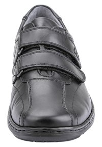 Black leather shoe with a rounded toe, featuring two Velcro straps and stitched accents along the sides and sole. Smooth texture overall.