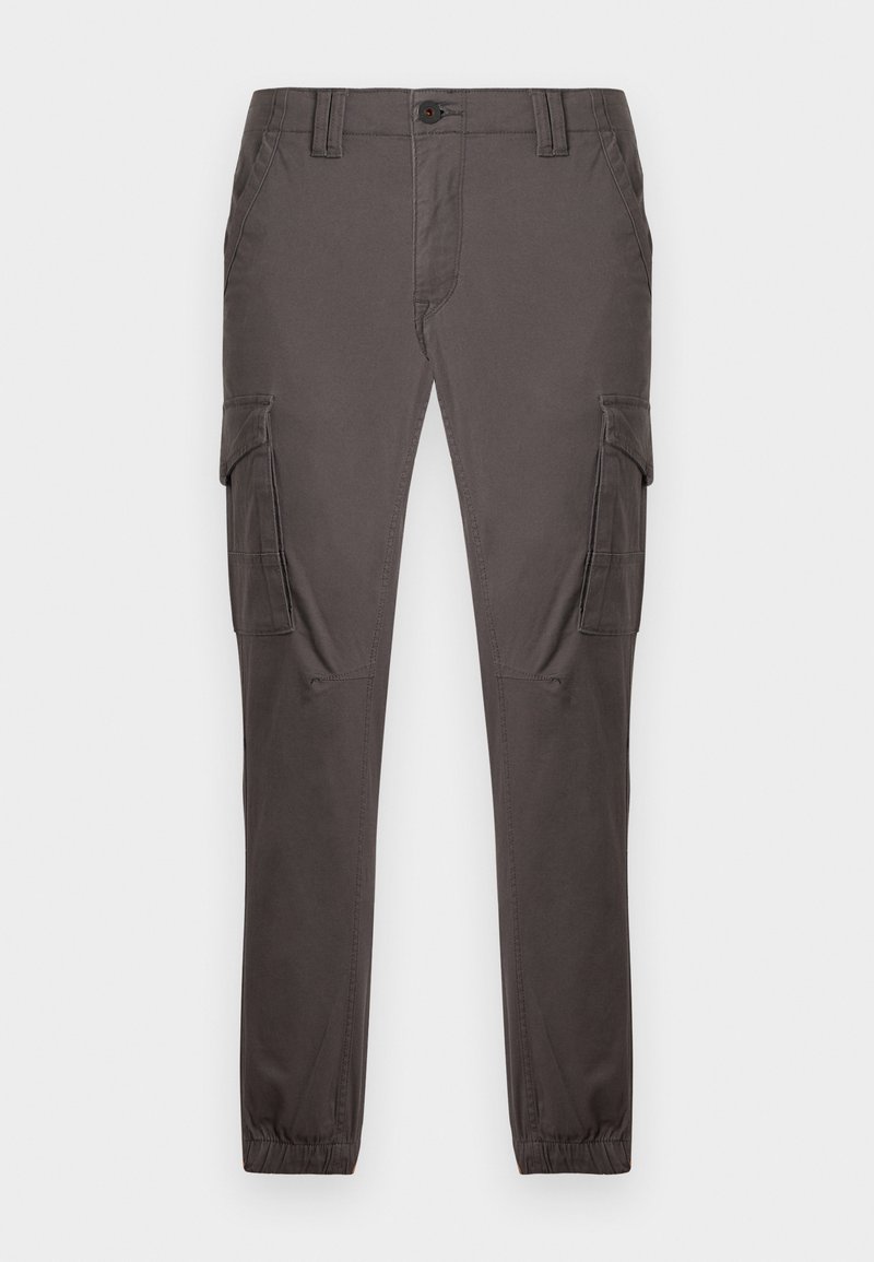 Tumši pelēkas kravas bikses ar sānu kabatām, koniskas kājas, elastīgi aproces un priekšējā daļā aizdare ar pogu. Gluda tekstūra.