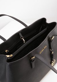 Borsa a mano nera in pelle con accessori in oro, multiple sezioni interne e tasche con zip. Esterno testurizzato e dettaglio del logo visibile.