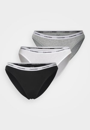Drie paar Calvin Klein slips in zwart, wit en grijs. Elk heeft een zachte tailleband met de merknaam in het zwart weergegeven.