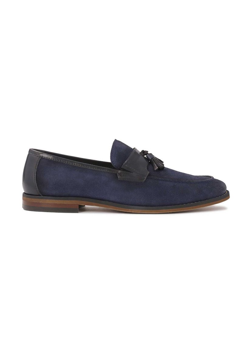 Loaferi din suede bleumarin, cu un accent de piele netedă, având o ciucure decorativ și o talpă plată maro. Design clasic, tip slip-on.