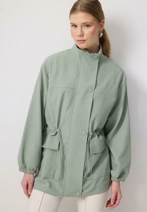 Groene jas van zacht materiaal met een hoge kraag, verstelbare trekkoord taille en voorzakken, met drukknoopsluiting en elastische manchetten.