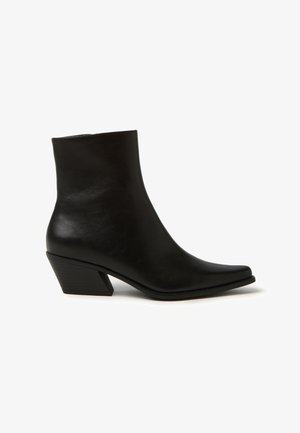 Stivale alla caviglia in pelle nera con punta appuntita e tacco a blocco. Texture liscia e design minimalista. Altezza del tacco di circa 5 cm.