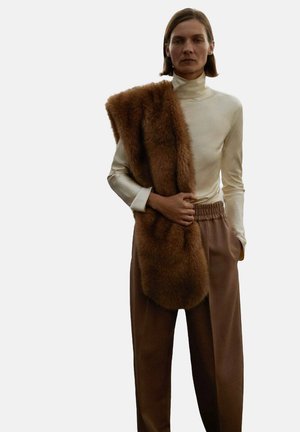 Un col roulé crème à manches longues associé à une écharpe en fourrure texturée marron et à un pantalon marron ample à taille haute. Tissu lisse et détails en peluche.