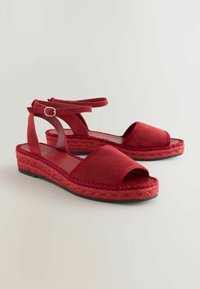 Rode suède espadrille sandalen met open tenen, een geweven jute tussenzool en enkelbandjes met zilveren hardware accenten.