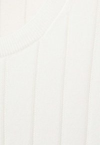 Gros plan d'un tissu tricot blanc avec des coutures côtelées verticales et un col arrondi.
