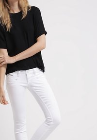 Black short-sleeve top paired with white skinny jeans. The outfit features a simple design and smooth texture with no visible patterns.