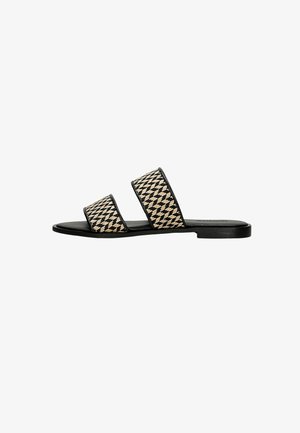 Schwarze und beige flache Sandalen mit zwei breiten geflochtenen Riemen, die ein Hahnentrittmuster aufweisen, und einem minimalistischen flachen Sohledesign.