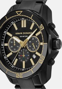 Črno nerjaveče jekleno uro s okroglo obliko obraza, zlatimi poudarki, tremi podmerami in prikazom datuma. Ima izrazite oznake ur in gumbke.